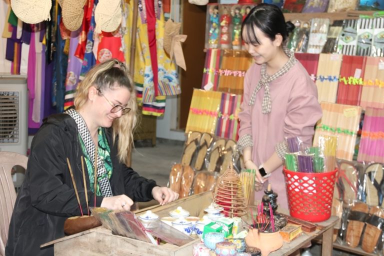 A Thuy Xuan Village artisan guiding visitors through the traditional incense-making process.