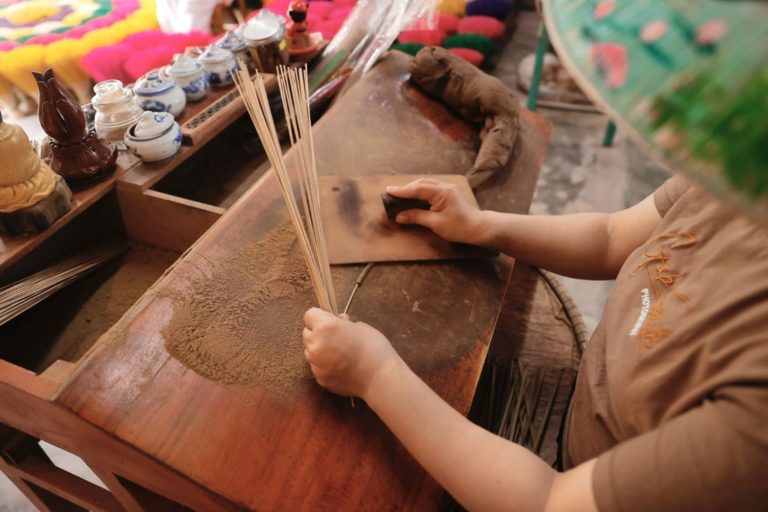 An artisan hand-rolling incense at Thuy Xuan Incense Village Hue