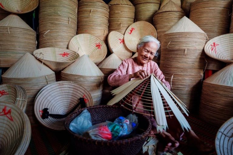Elderly woman making conical hats at Tay Ho traditional craft village in Hue